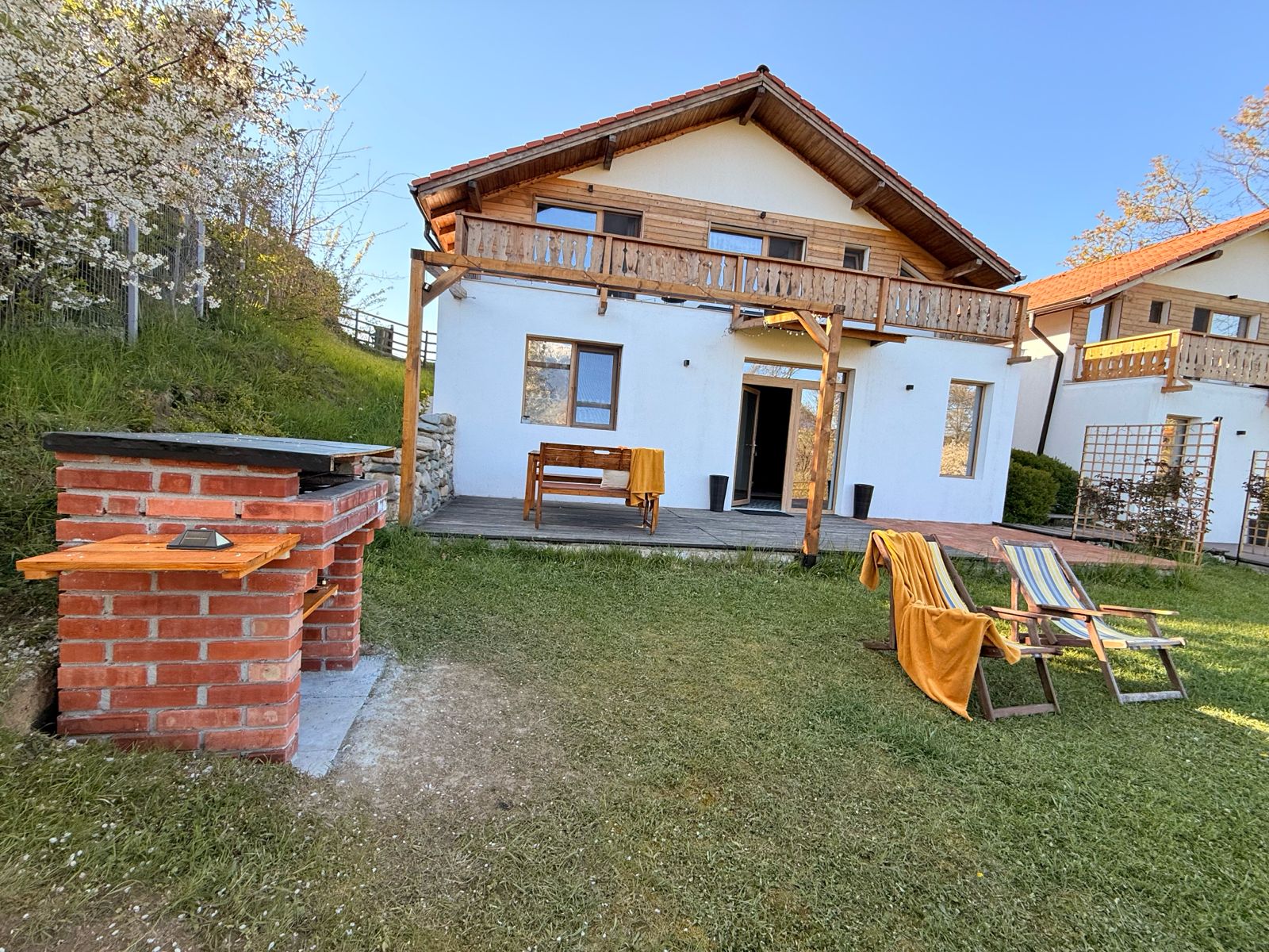 Terasa cu pergolă și loc de joacă în fundal